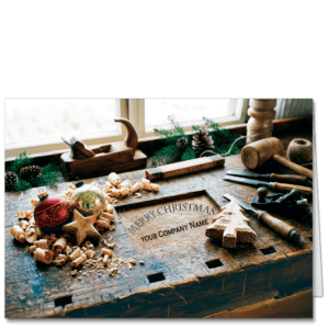 Construction company Christmas cards display a beautifully used wood workshop bench that features your company name and holiday greeting embedded in the wood. Ornaments and traditional wood working tools rest on the bench.