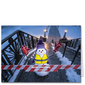 These construction Christmas cards feature a jaunty snowman wearing a yellow safety vest. He stands at the top of an icy staircase with your company name and greeting on the red and white striped barricade in front.